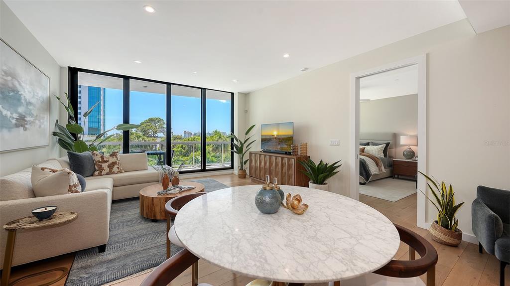 A living and dining area features a marble table, sectional sofa, and floor-to-ceiling windows — 300 S PINEAPPLE AVENUE UNIT 302, SARASOTA, FL