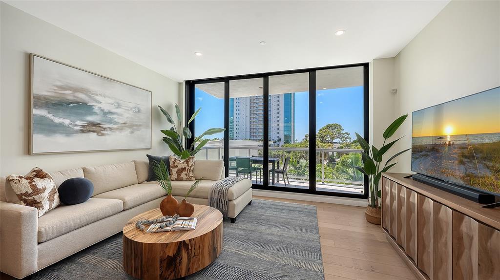 A modern living room features a sectional sofa, wood coffee table, and floor-to-ceiling windows — 300 S PINEAPPLE AVENUE UNIT 302, SARASOTA, FL