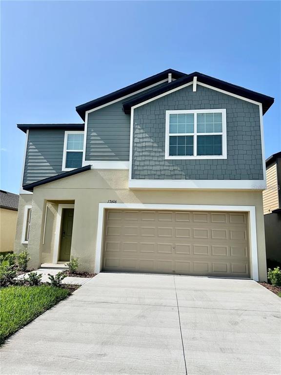 A two-story house features a tan stucco exterior, blue siding, and a two-car garage — 17606 HAPPYTRAILS STREET, LAND O LAKES, FL