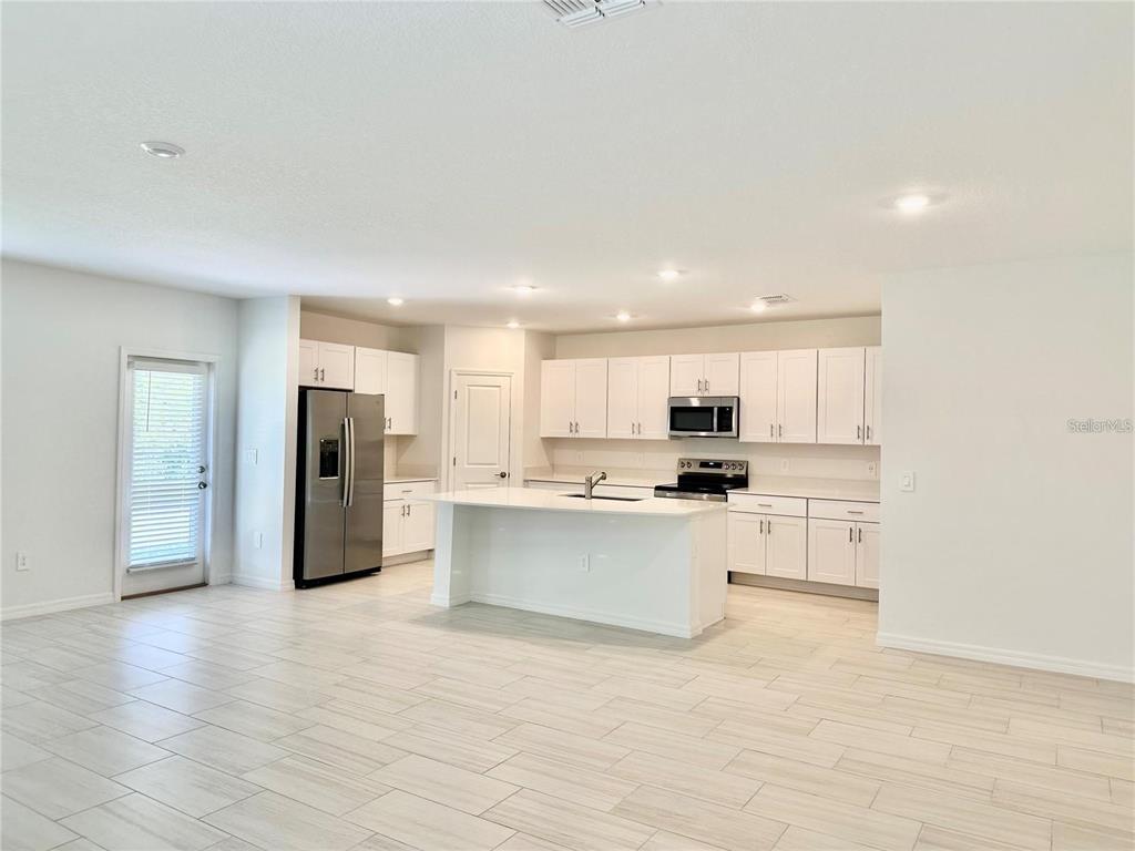 A modern kitchen features white cabinetry, stainless steel appliances, and a central island — 17606 HAPPYTRAILS STREET, LAND O LAKES, FL