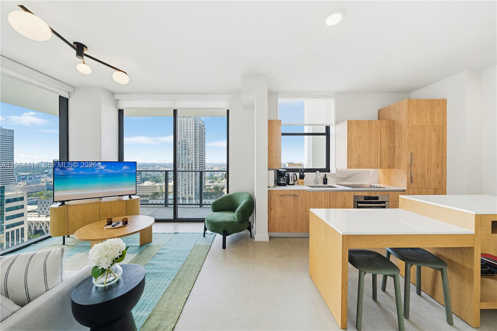 A modern apartment living area features a kitchen, dining island, and balcony with city views — 11 NE 6th # 2901, Miami FL 33132, MIAMI, FL