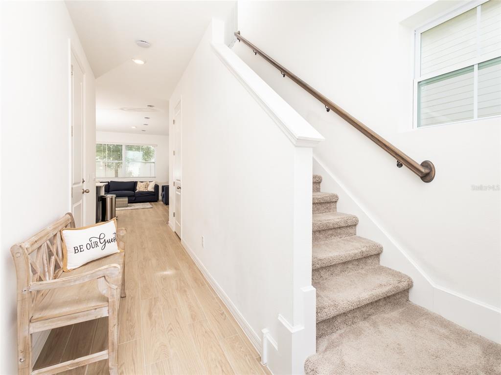 A hallway features light wood-look flooring, a carpeted staircase with a handrail, and a bench — 783 LONGBOAT DRIVE, DAVENPORT, FL