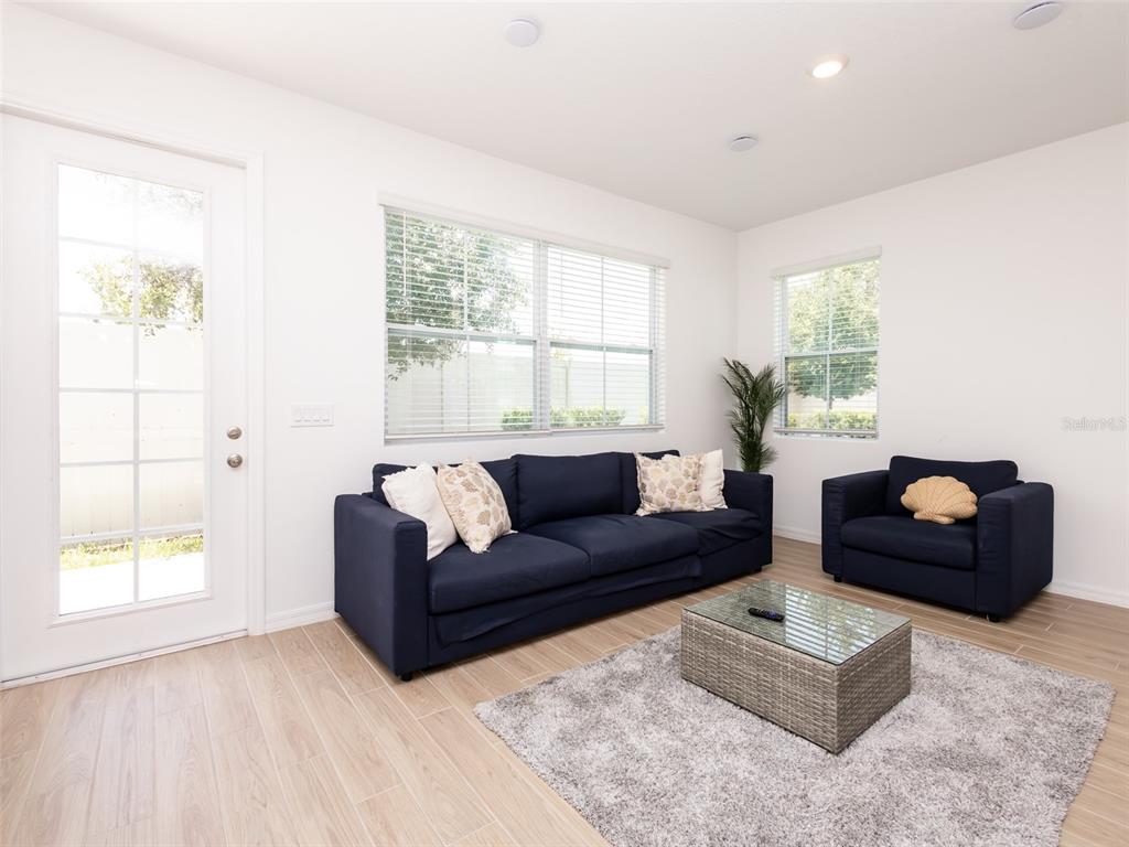 A living room features a navy sofa and armchair, a glass-topped coffee table, and tile flooring — 783 LONGBOAT DRIVE, DAVENPORT, FL