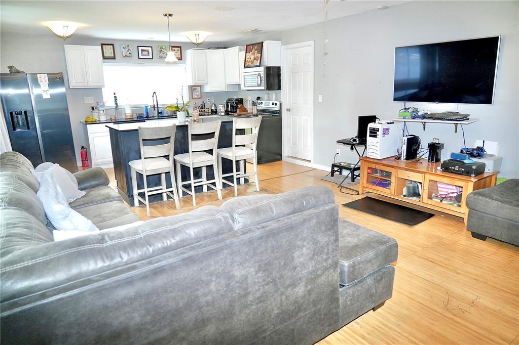 An open-concept living room and kitchen with white cabinets, a dark island, and wood flooring — 1513 W PATTERSON STREET, TAMPA, FL