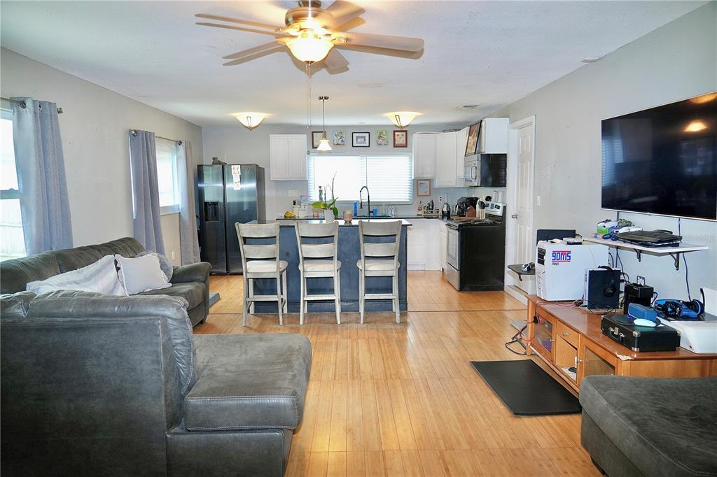 An open-concept living room and kitchen featuring wood-look flooring, a sectional sofa, and island seating — 1513 W PATTERSON STREET, TAMPA, FL