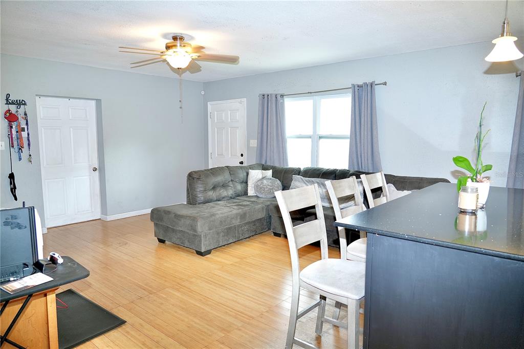 A living room with light wood floors, a gray sectional sofa, and a kitchen island — 1513 W PATTERSON STREET, TAMPA, FL