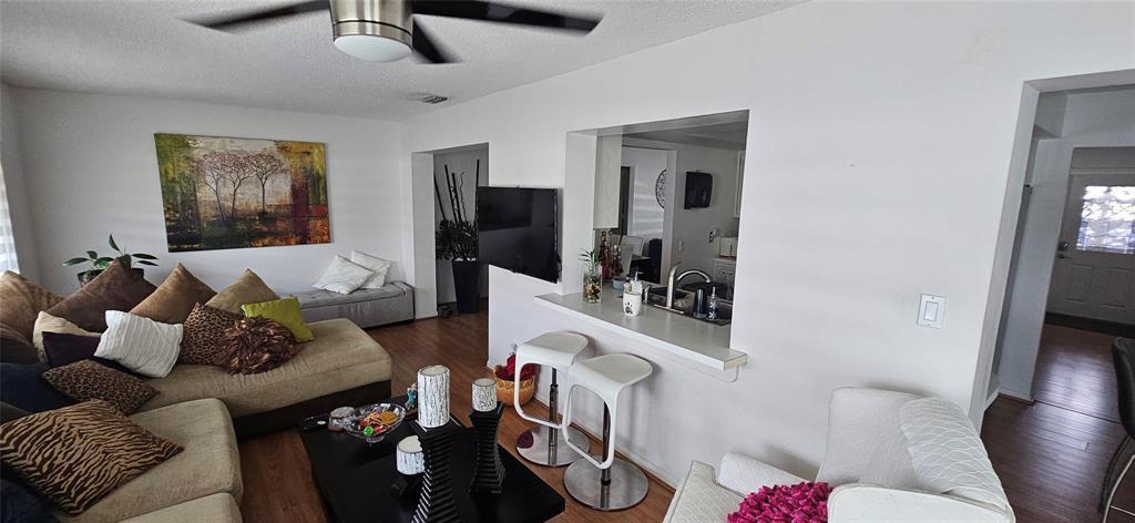 A living room features a sectional sofa, a breakfast bar with stools, and wood flooring — 7000 NW 11th Street, Margate FL 33063, MARGATE, FL