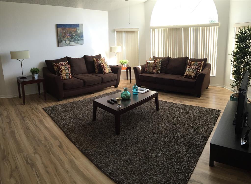 A living room features two brown sofas, a coffee table, and a large area rug — 2480 SWEETWATER CLUB CIRCLE UNIT 98, KISSIMMEE, FL