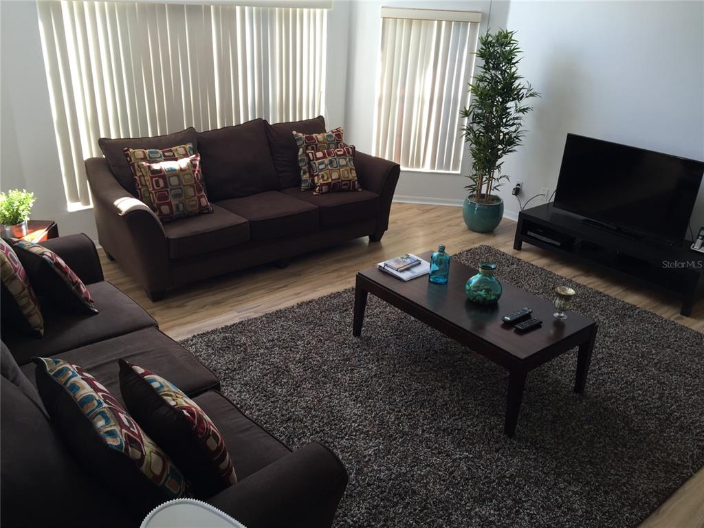 A living room features two brown sofas, a coffee table, and a television on a stand — 2480 SWEETWATER CLUB CIRCLE UNIT 98, KISSIMMEE, FL