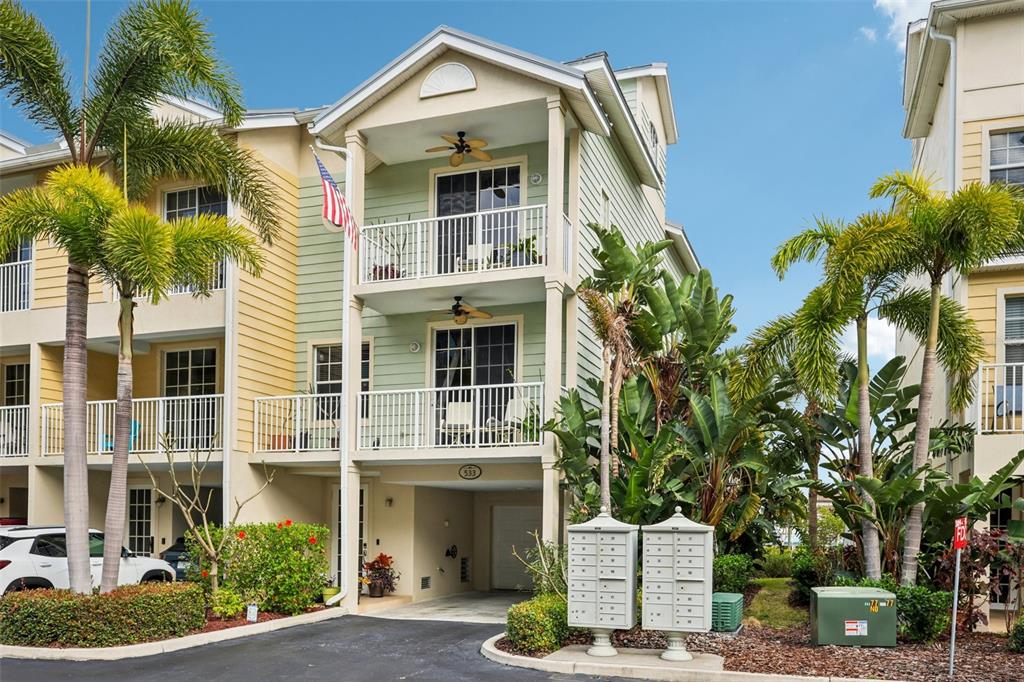 A three-story townhouse with two balconies, a ground-level garage, and mailboxes in the foreground — 533 BAHIA BEACH BOULEVARD, RUSKIN, FL