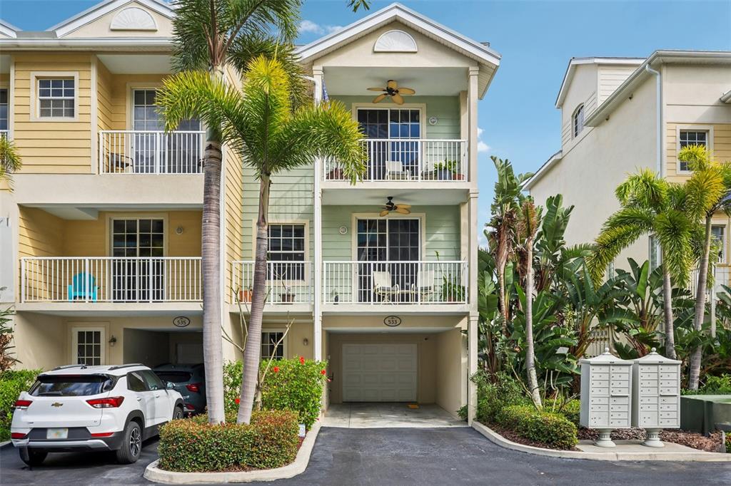 An exterior view of a multi-story townhouse with balconies, a garage, and palm trees — 533 BAHIA BEACH BOULEVARD, RUSKIN, FL