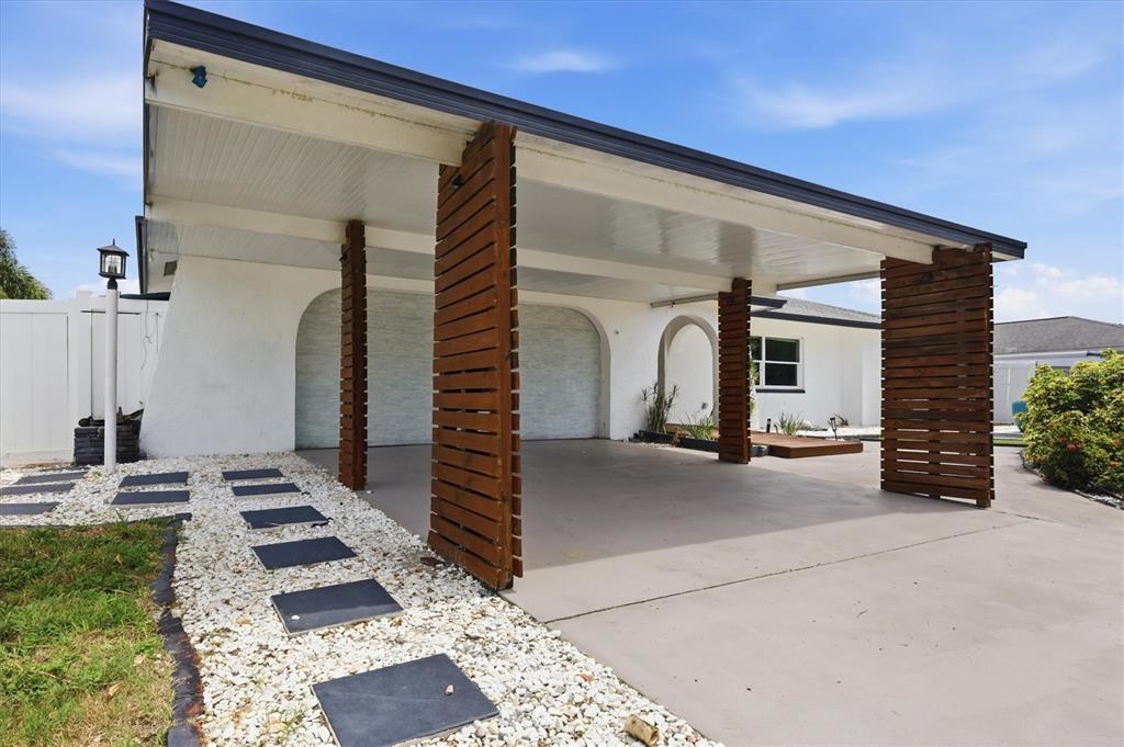 A white house features a carport with wooden slat columns and a stone walkway — 3615 EGERTON CIRCLE, SARASOTA, FL