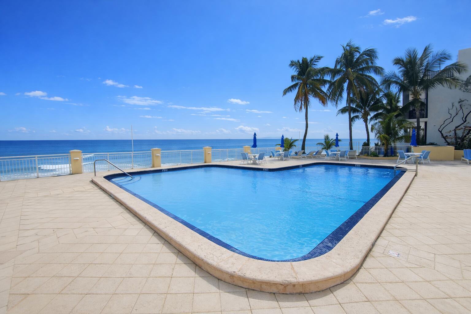 An outdoor swimming pool overlooks the ocean with palm trees and a patio area — 3475 S Ocean Boulevard # 3020, Palm Beach FL 33480, PALM BEACH, FL