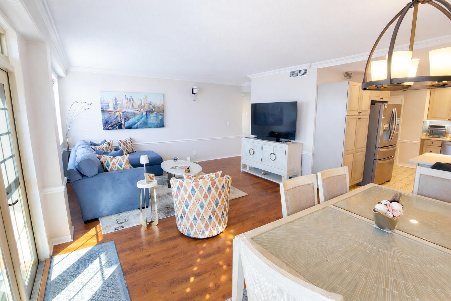 An open-concept living and dining area features hardwood floors, a blue sectional, and a television — 3475 S Ocean Boulevard # 3020, Palm Beach FL 33480, PALM BEACH, FL