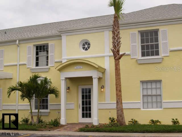 A two-story yellow building features a central covered entryway, white shutters, and a palm tree — 5248 BEACH DRIVE SE UNIT 5248, ST PETERSBURG, FL