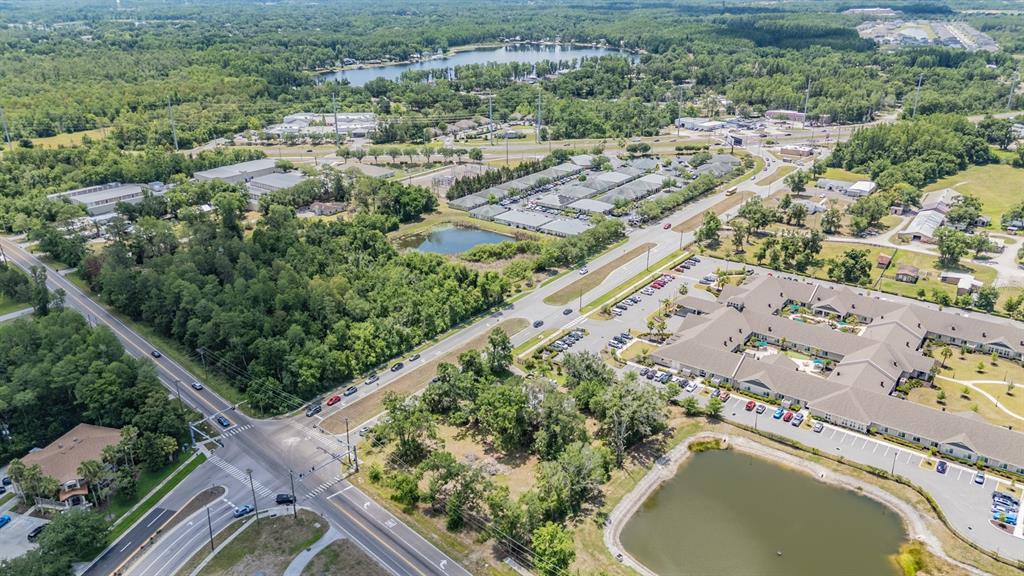 An aerial view shows a commercial building complex, a pond, and surrounding roads and trees — 18950 SUNLAKE BOULEVARD, LUTZ, FL
