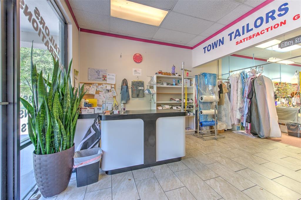 The interior of a tailor shop features a service counter, clothing racks, and a large plant — 3662 LITHIA PINECREST ROAD, VALRICO, FL