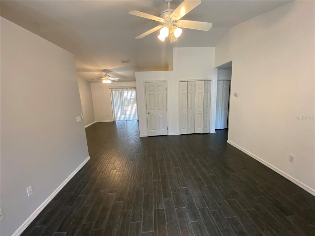 A living room with dark wood-look tile flooring, white walls, and two ceiling fans — 9195 SE 163RD STREET, SUMMERFIELD, FL