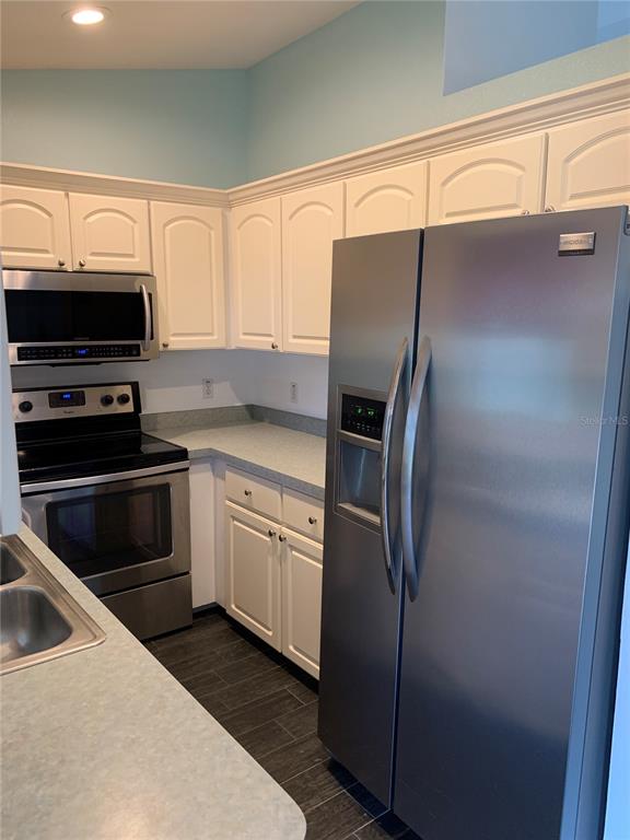 A kitchen features white cabinets, stainless steel appliances, and a light-colored countertop — 9195 SE 163RD STREET, SUMMERFIELD, FL