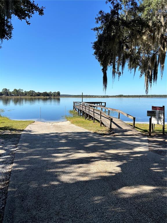 A concrete boat ramp leads to a wooden pier extending into a calm lake — 14348 NE 252ND COURT ROAD, FORT MC COY, FL