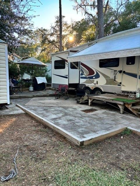 A recreational vehicle is parked on a paved patio area next to a wooden deck — 14348 NE 252ND COURT ROAD, FORT MC COY, FL