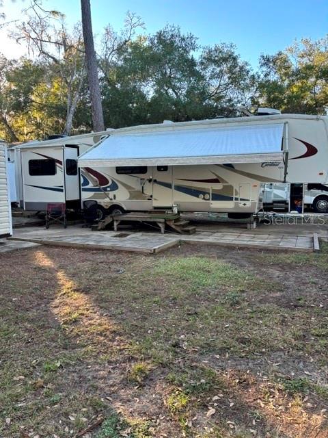 A large fifth-wheel recreational vehicle is parked on a paved pad in a wooded area — 14348 NE 252ND COURT ROAD, FORT MC COY, FL