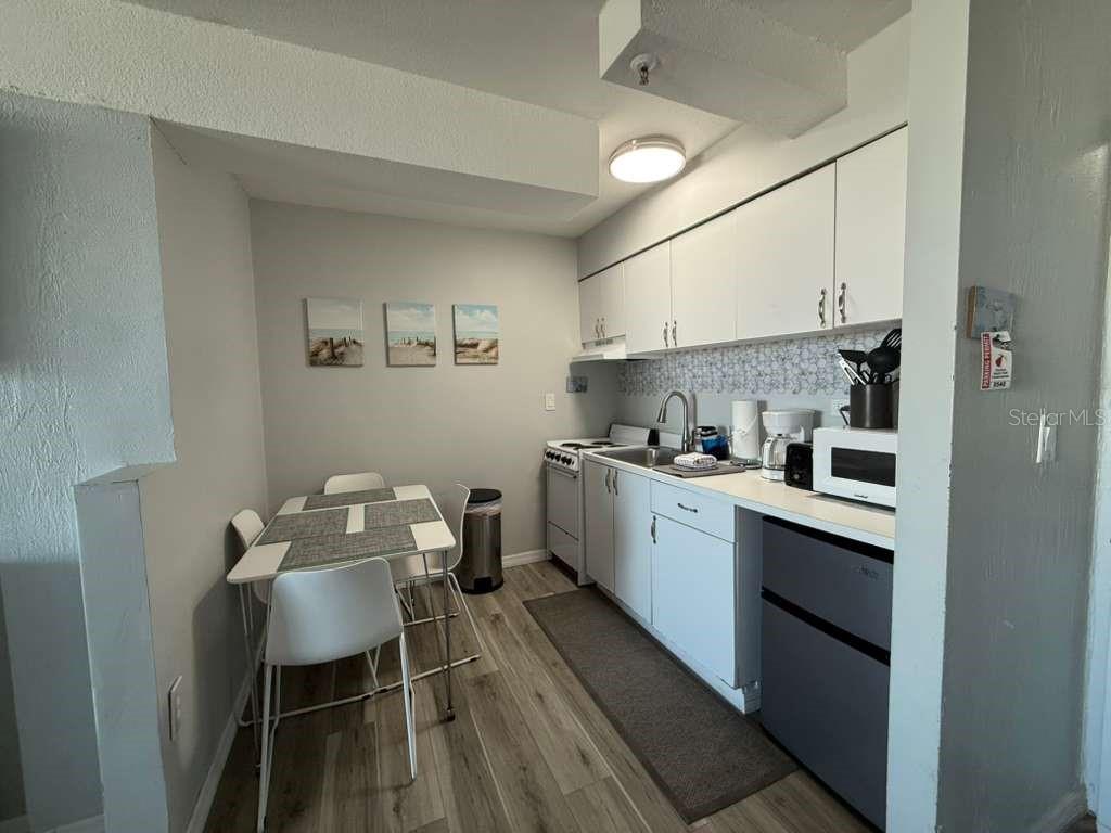 A small kitchen features white cabinets, a dining table for two, and light wood flooring — 800 N ATLANTIC AVENUE UNIT 420, DAYTONA BEACH, FL