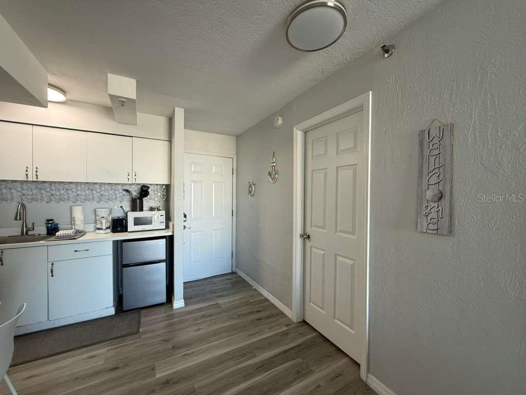 A small kitchen area features white cabinets, a mini-fridge, and wood-look flooring — 800 N ATLANTIC AVENUE UNIT 420, DAYTONA BEACH, FL