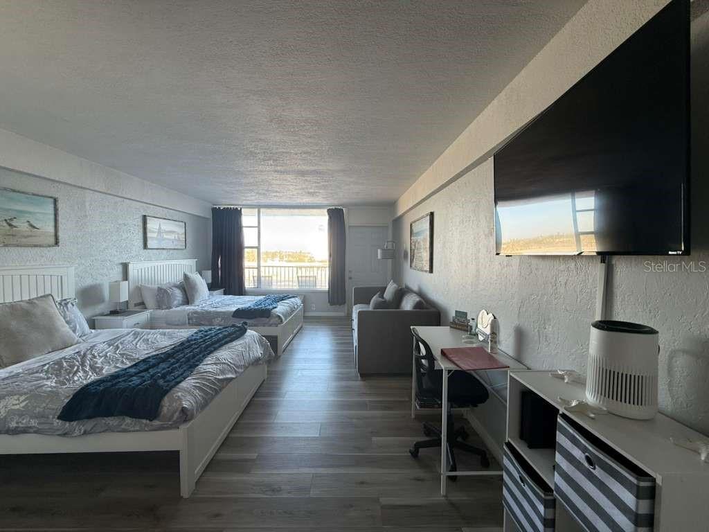 A hotel-style room features two beds, a sofa, a desk, and a large wall-mounted television — 800 N ATLANTIC AVENUE UNIT 420, DAYTONA BEACH, FL