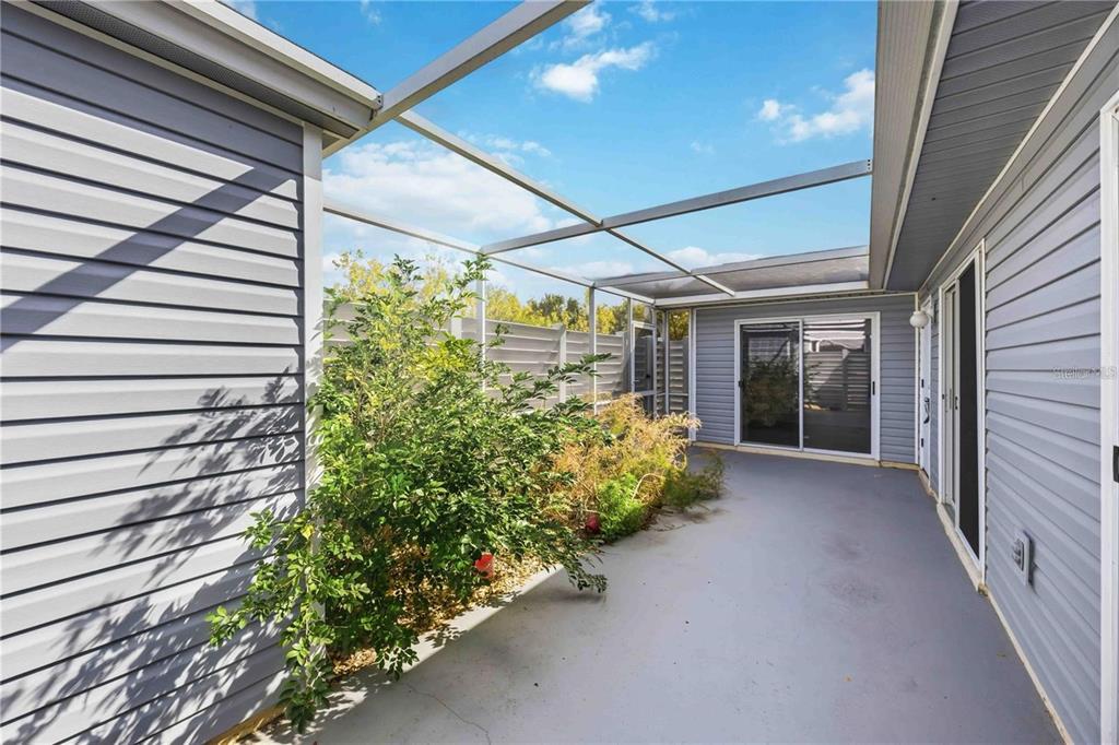 A screened-in patio with gray siding, a concrete floor, and a small garden area — 3300 LOVELAND BOULEVARD UNIT 2501, PUNTA GORDA, FL