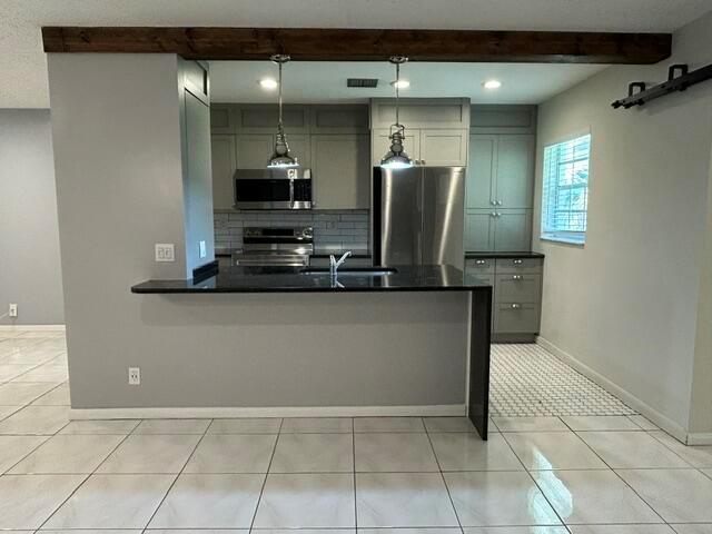 A kitchen features gray cabinets, stainless steel appliances, a black countertop, and a wooden beam — 5270 Nesting Way # B, Delray Beach FL 33484, DELRAY BEACH, FL