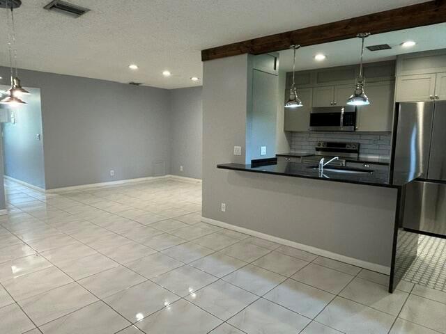 A kitchen with a black countertop island opens into a tiled living area — 5270 Nesting Way # B, Delray Beach FL 33484, DELRAY BEACH, FL