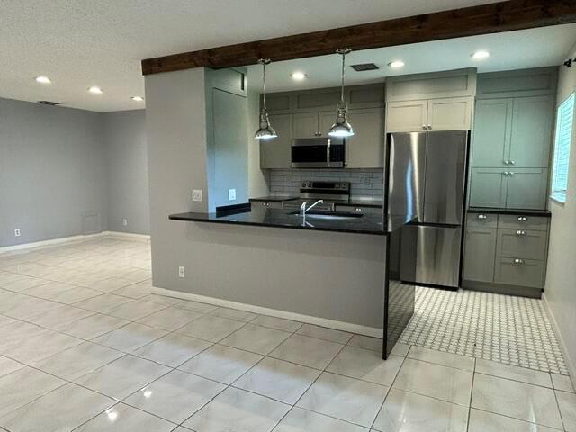 A kitchen features gray cabinets, stainless steel appliances, a black countertop, and tile flooring — 5270 Nesting Way # B, Delray Beach FL 33484, DELRAY BEACH, FL