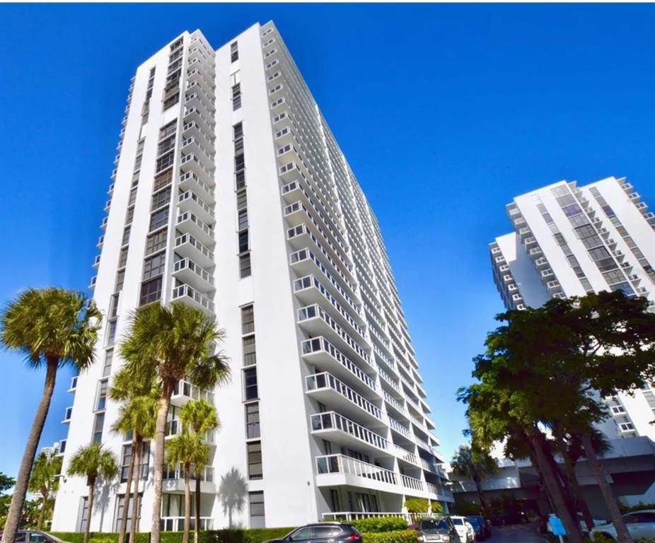 A tall white residential high-rise building stands against a clear blue sky — 20505 E COUNTRY CLUB DRIVE UNIT 534, MIAMI, FL