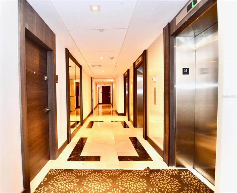 A modern hallway features a polished tile floor with dark accents and stainless steel elevators — 20505 E COUNTRY CLUB DRIVE UNIT 534, MIAMI, FL