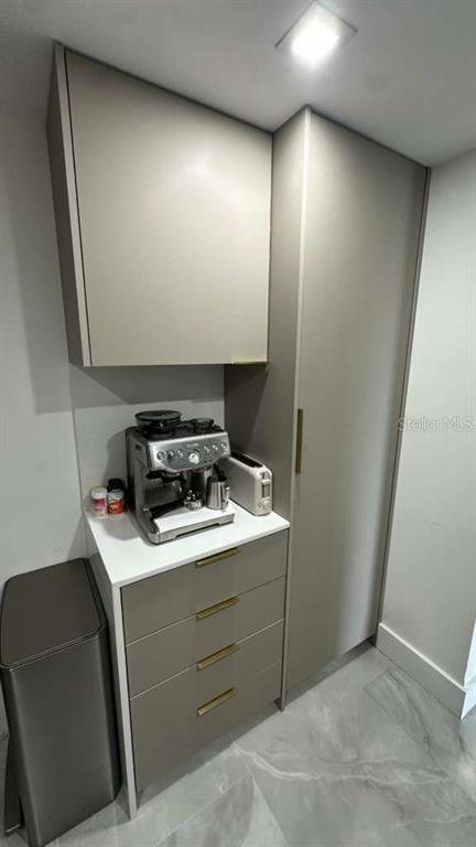 A modern kitchen coffee station features light gray cabinetry, gold hardware, and a white countertop — 20505 E COUNTRY CLUB DRIVE UNIT 534, MIAMI, FL