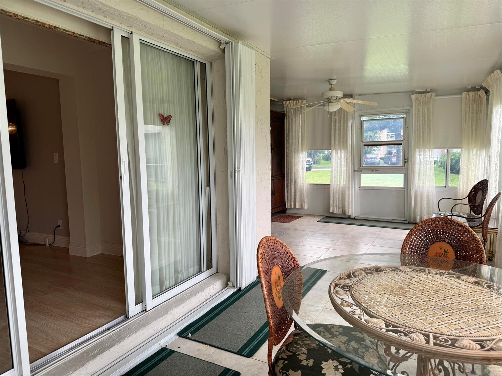 A sunroom features a glass-topped wicker dining set, sliding glass doors, and tile flooring — 1460 NW 19th Terrace # a, Delray Beach FL 33445, DELRAY BEACH, FL