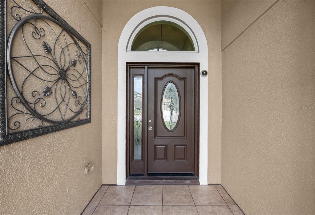 A brown front door with a glass insert and sidelight sits under an arched transom — 4124 101ST AVENUE E, PARRISH, FL