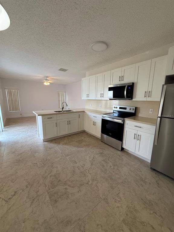 A kitchen with white cabinets, stainless steel appliances, and light-colored tile flooring — 315 EDGEWOOD COURT, KISSIMMEE, FL