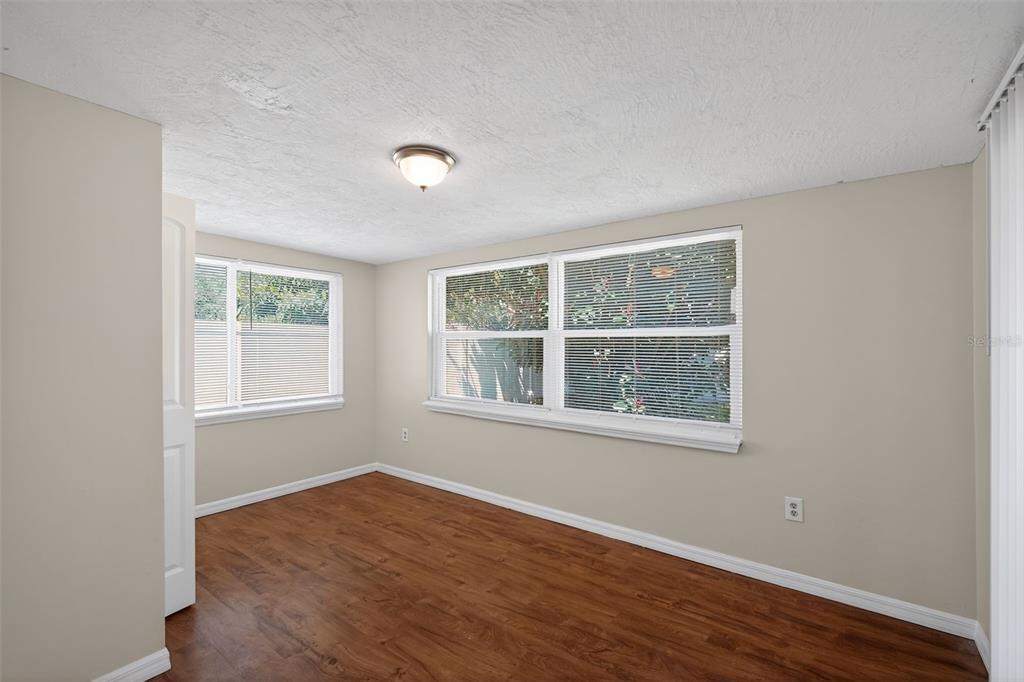 A covered concrete patio features a red front door, a large window, and spiral columns — 3537 SEFFNER DRIVE, HOLIDAY, FL