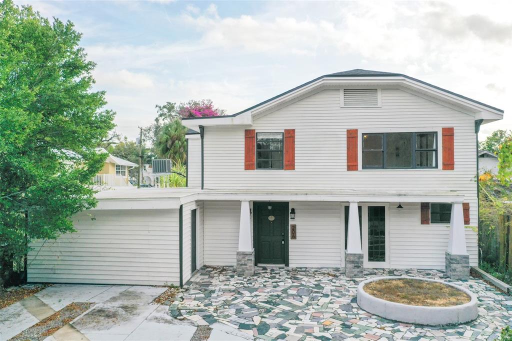 A two-story white house features a stone patio, a circular planter, and wooden shutters — 206 W FRIERSON AVENUE, TAMPA, FL