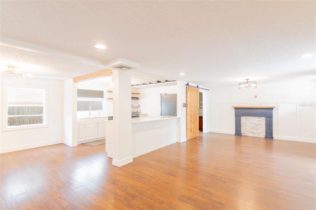 An open-concept living area features wood flooring, a kitchen island, and a dark fireplace mantel — 206 W FRIERSON AVENUE, TAMPA, FL