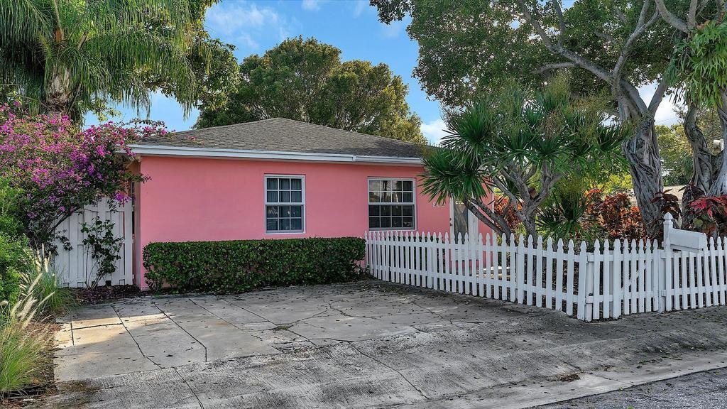 A pink single-story house features a white picket fence and a concrete driveway — 802 N J Street, FL 33460, FL