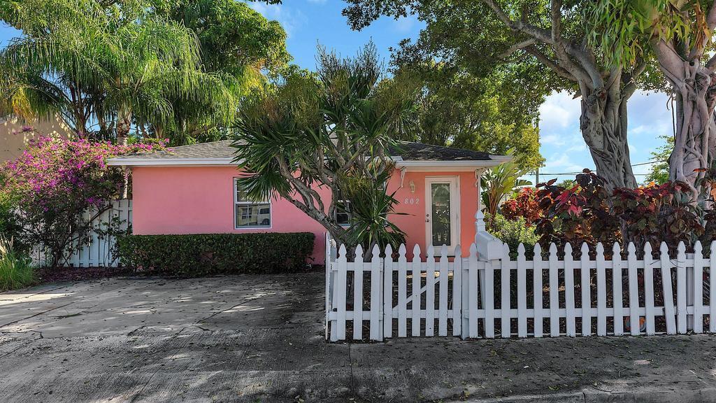A pink single-story house with a white picket fence and a paved driveway — 802 N J Street, FL 33460, FL