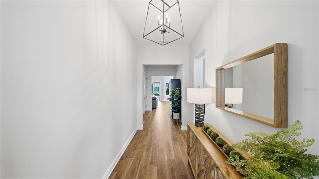 A hallway features wood-look flooring, a geometric pendant light, and a wooden console table — 203 TESORO TERRACE, ST AUGUSTINE, FL