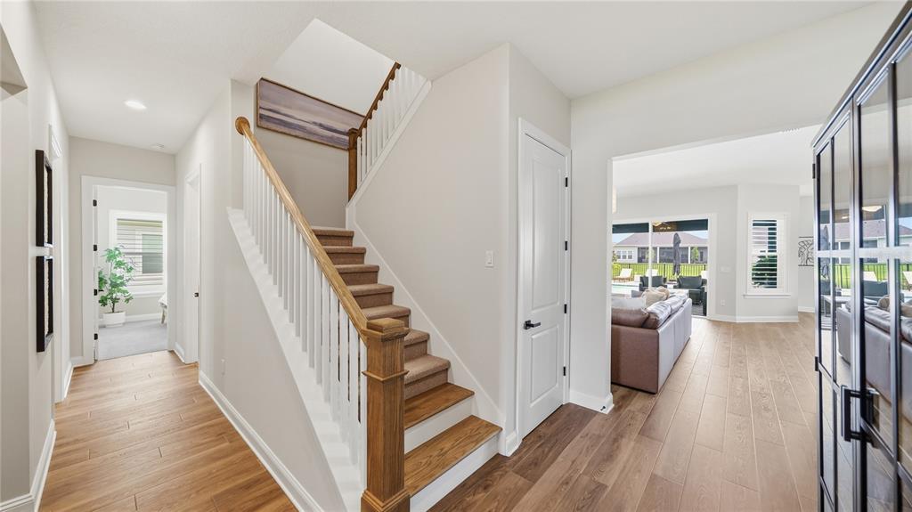 A foyer features a wooden staircase with white railings, light wood flooring, and an open living area — 203 TESORO TERRACE, ST AUGUSTINE, FL