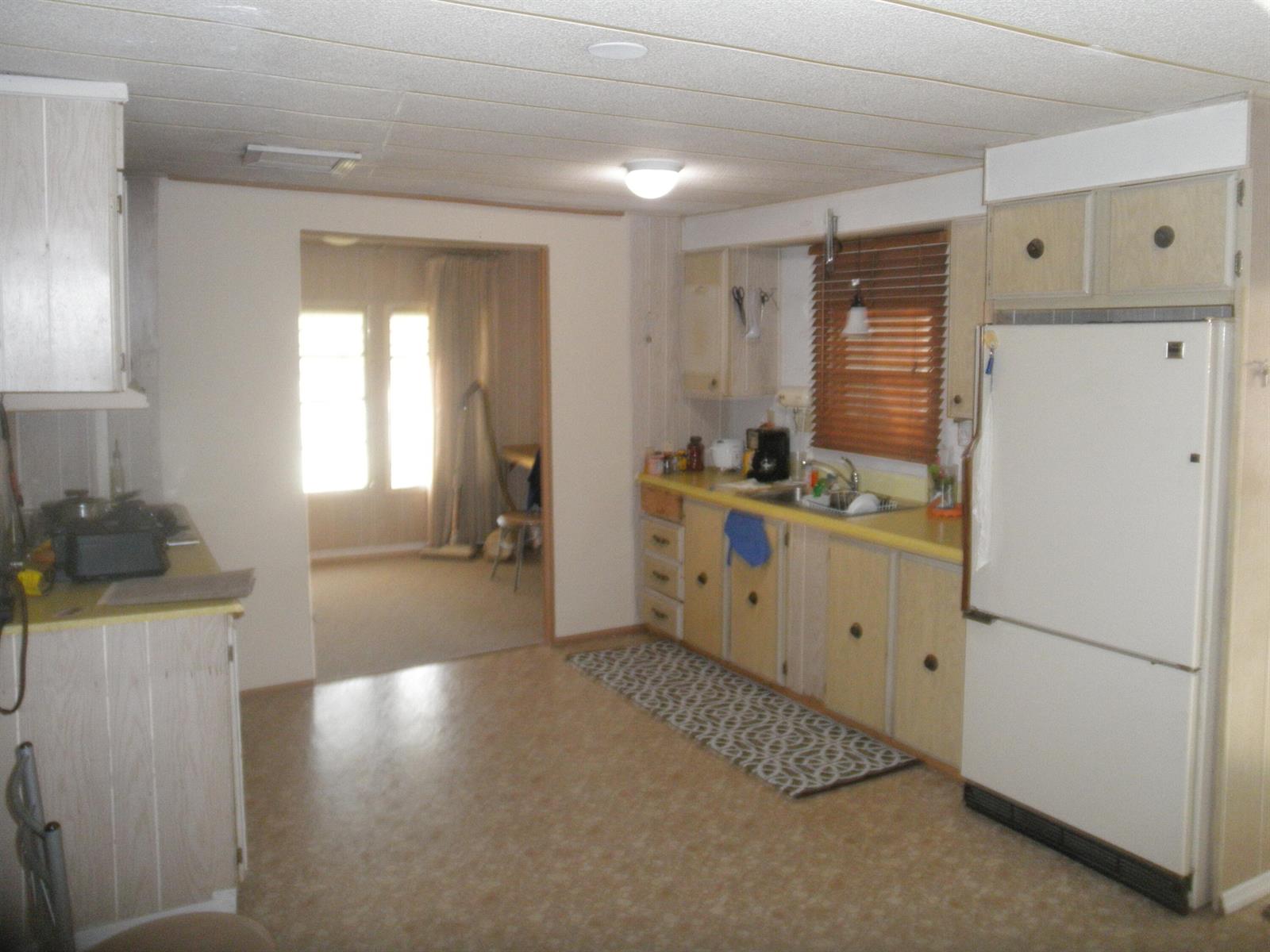 A kitchen features light wood cabinets, yellow countertops, a white refrigerator, and a patterned rug — 4544 Sunset Ranch Road, West Palm Beach FL 33415, WEST PALM BEACH, FL