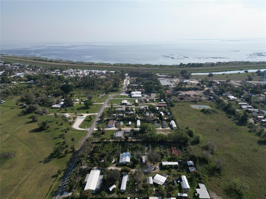 An aerial view shows a residential area with mobile homes near a large body of water — 3321 38th Avenue, Okeechobee FL 34974, OKEECHOBEE, FL