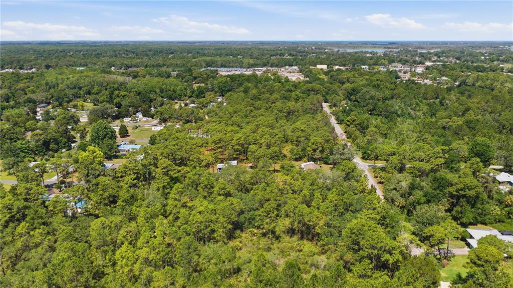 An aerial view shows a wooded residential area with scattered houses and a paved road — 8266 W ANNA GAIL LANE, CRYSTAL RIVER, FL