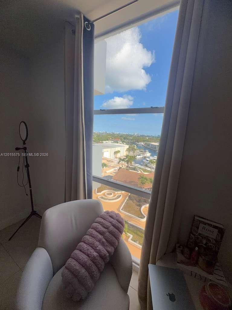 A room with a chair and a window overlooking a marina and city skyline — 13499 Biscayne Blvd # 906, North Miami FL 33181, NORTH MIAMI, FL